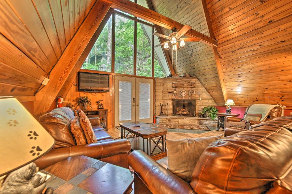 a living room with leather furniture and a large window at A-Frame Gatlinburg Cabin with Deck and Private Hot Tub in Gatlinburg