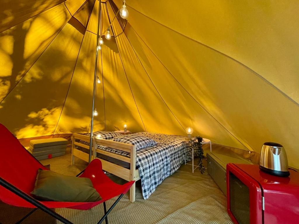 1 dormitorio con 1 cama y 1 silla en una tienda de campaña en Tente Indiana Chênes - La Téouleyre en Saint-Julien-en-Born
