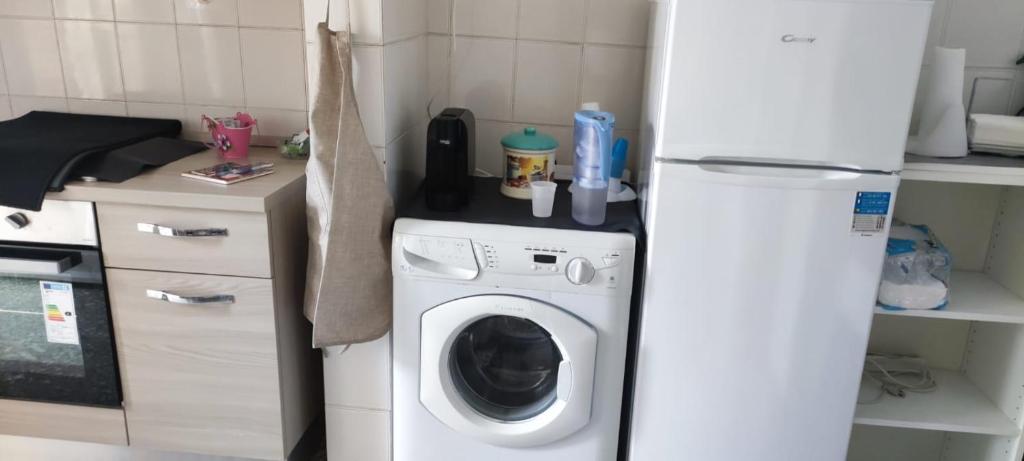 a kitchen with a washing machine and a refrigerator at Appartamento luminoso, semplice con ogni comfort in Lido di Ostia