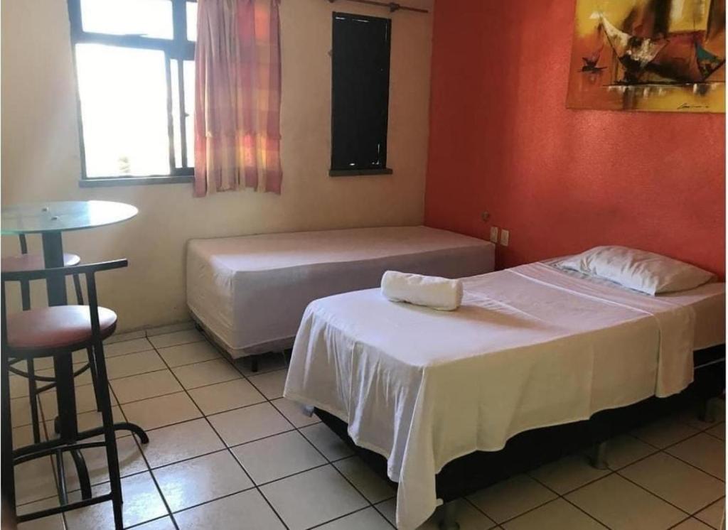 a room with two beds and a table and a table at pousada Sol e Praia in Fortaleza