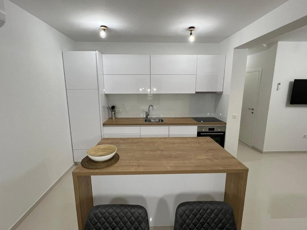 cocina con armarios blancos y mesa de madera en Residence Doli en Vrsi