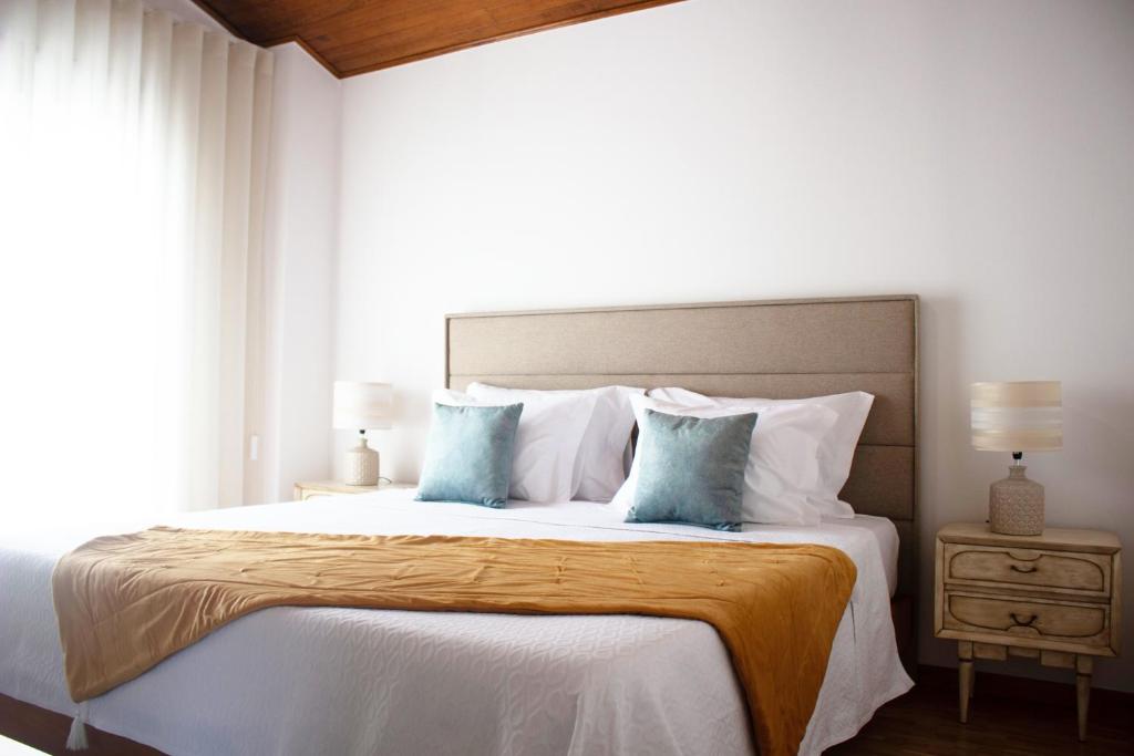 a bedroom with a large bed with blue pillows at Helena's Family House in Pinhão
