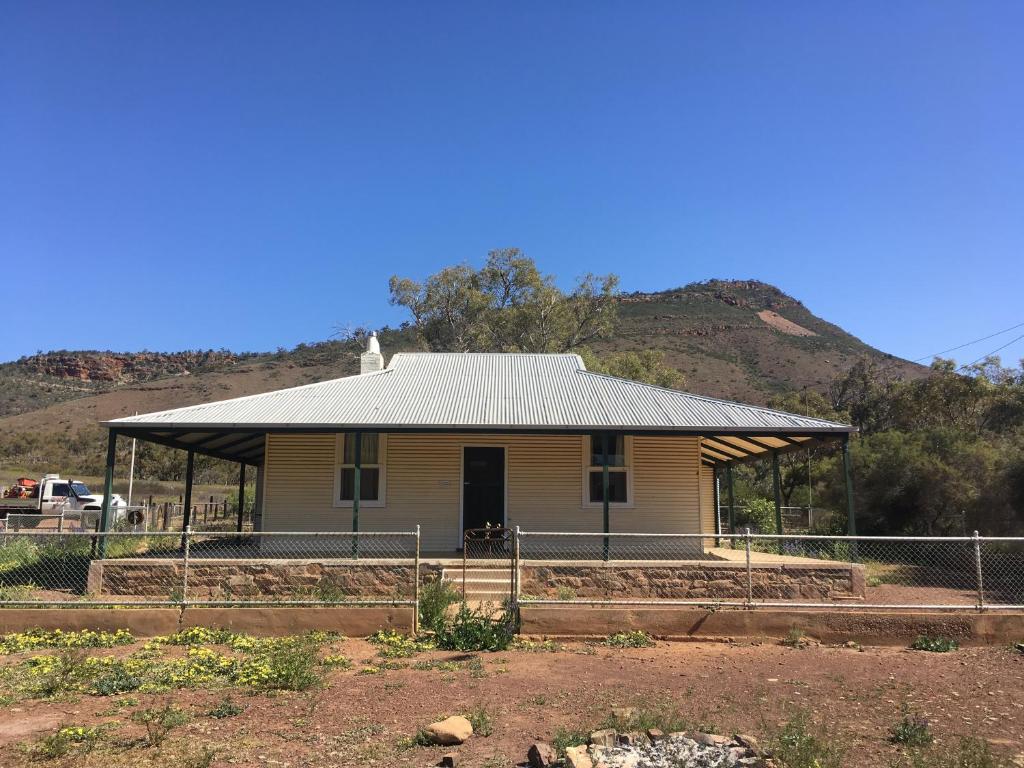 a house with a fence in front of a mountain at Old Homestead - The Dutchmans Stern Conservation Park in Quorn