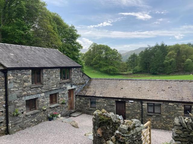 two old stone buildings with trees in the background at Crookabeck B&B in Patterdale