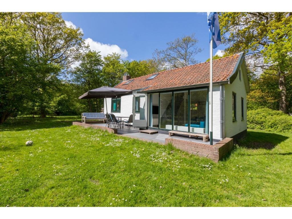 uma pequena casa com um pátio e um guarda-chuva em Attractive vacation home with spacious garden em Vrouwenpolder