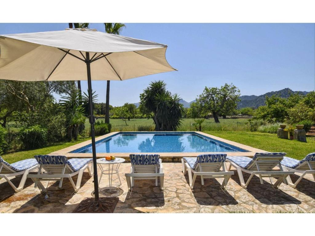 een zwembad met een parasol en stoelen en een tafel met een parasol bij Belvilla by OYO Tonina in Pollença
