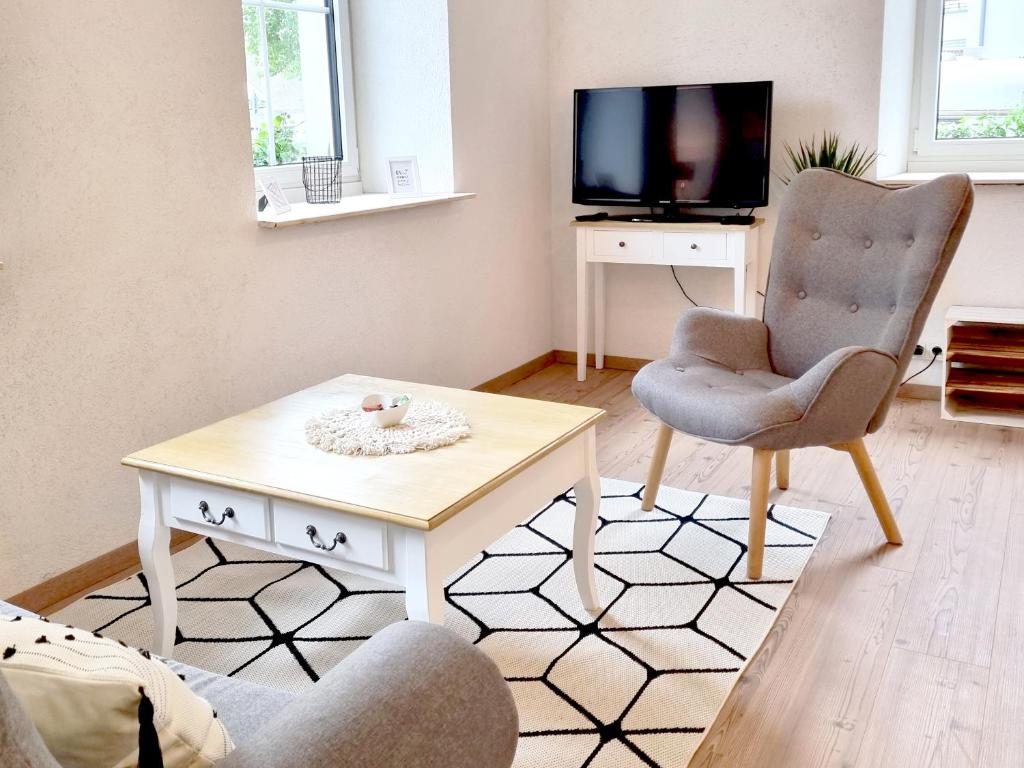 a living room with a table and a chair and a tv at Apartment Kerbholz - zwischen Südschwarzwald und Schweiz in Klettgau