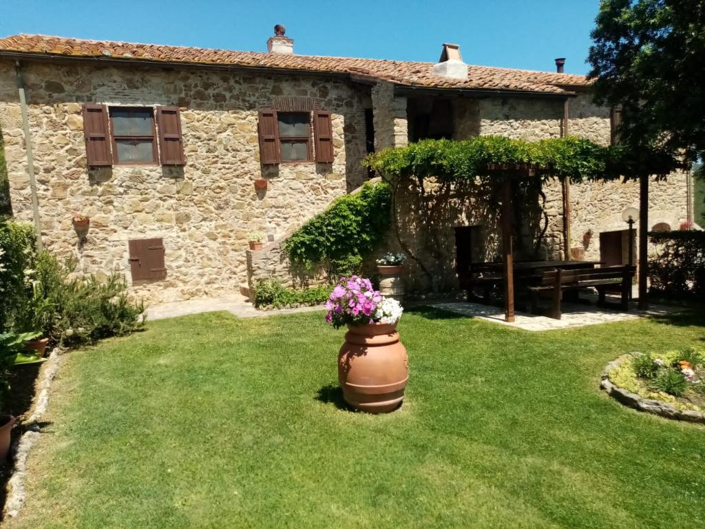 uma casa de pedra com um vaso de flores no quintal em Agriturismo “Sterrati” em Valpiana