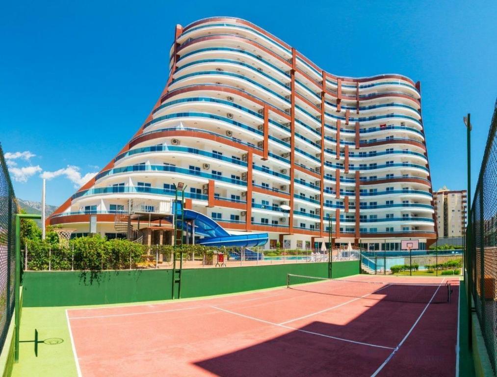 um grande edifício com um campo de ténis em frente em Lumos SPA ALL-IN apartment in Luxury resort full facilities em Alanya