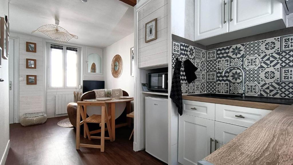 une cuisine avec des placards blancs et une petite table avec des chaises dans l'établissement Logement dans maison de pêcheur, au Tréport