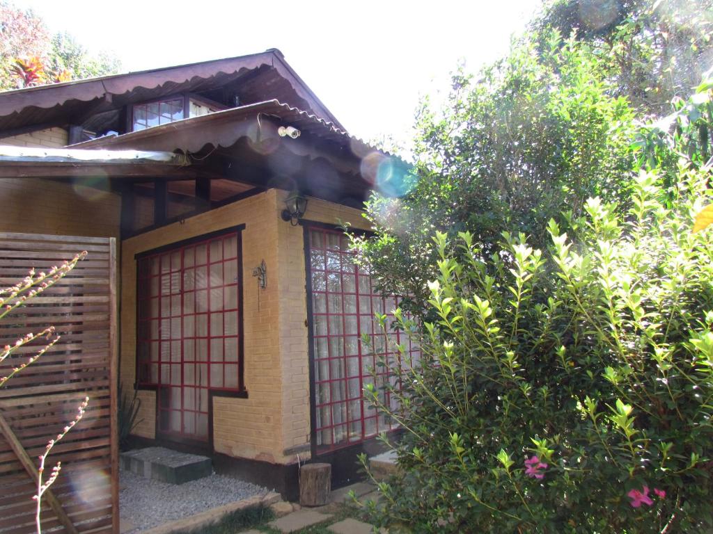 een huis met een rode deur en wat bomen bij Chalé Pakere Montanha Lumiar - Conforto a mais de 1000 metros de altitude junto a natureza, lareira, wifi, piscina, sauna e água de nascente in Lumiar