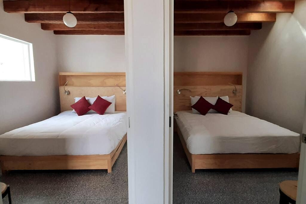 2 camas con almohadas rojas en una habitación en 125 DONCELES TERRAZA PRIVADA CENTRO HISTÓRICO CDMX, en Ciudad de México