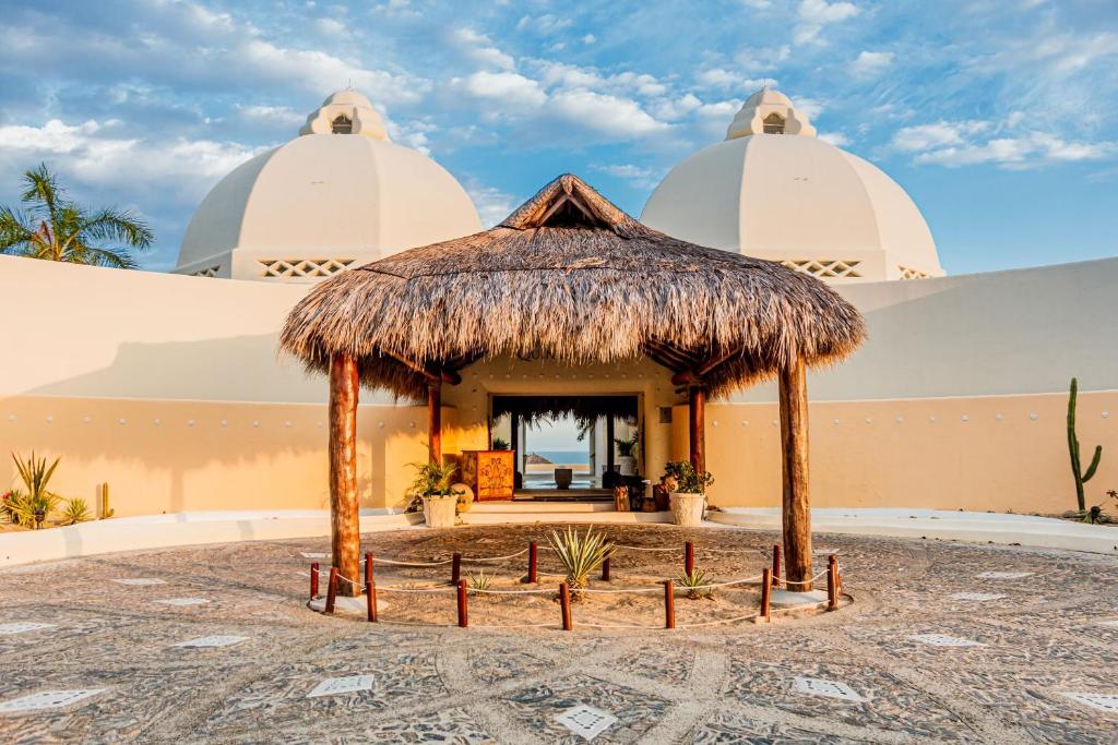 a hut in front of a building with two domes at Quinta Real Huatulco in Santa Cruz Huatulco