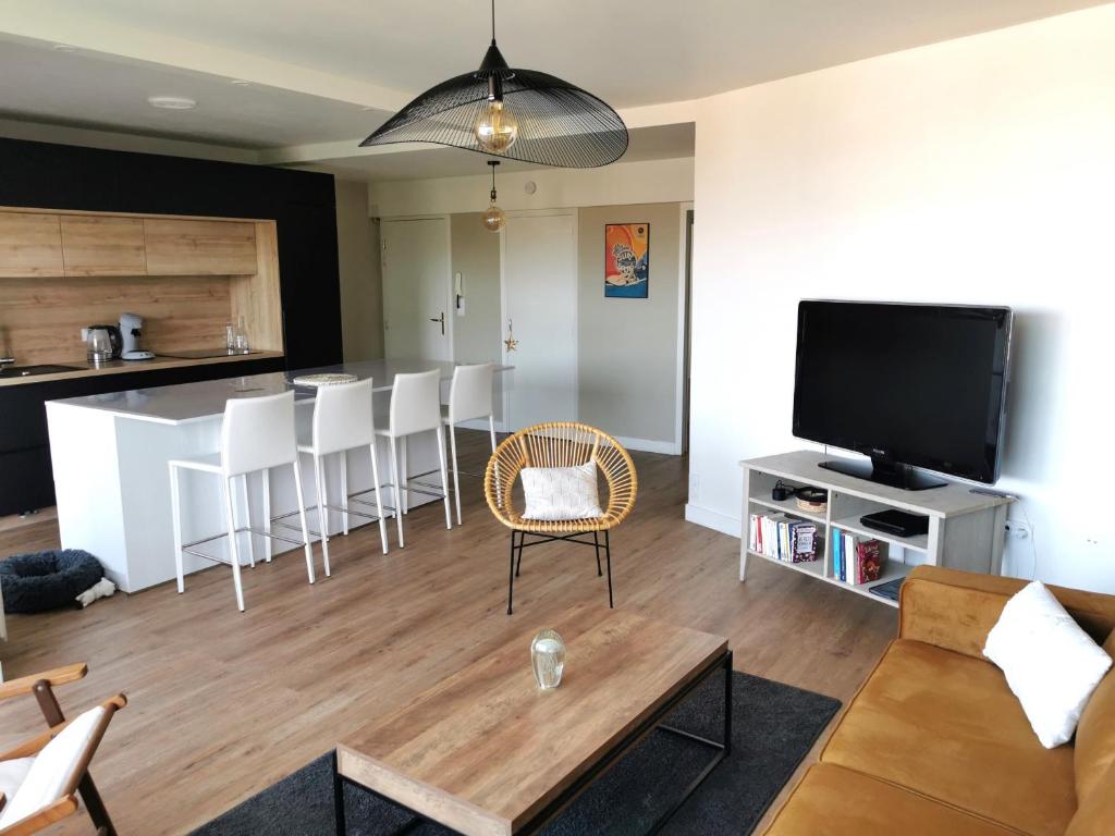 a living room with a couch and a television at Les Pins de l'Ocean - A 1km de la mer in Les Sables-dʼOlonne