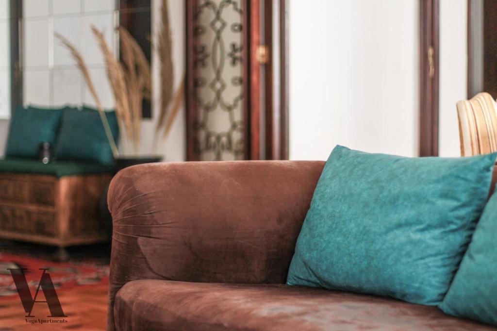 a brown couch with blue pillows in a living room at Voga Apartments Sta Catarina in Porto
