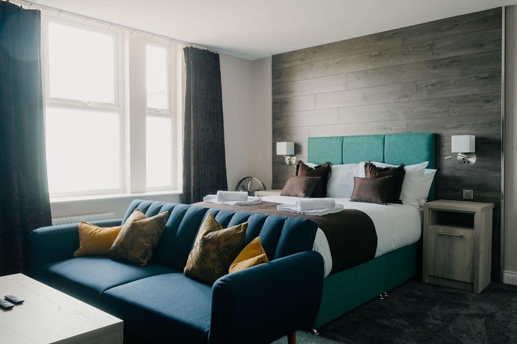 a bedroom with a large bed with a blue couch at The Portland in Ashington
