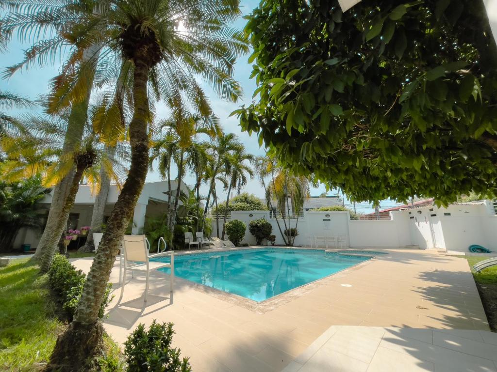 a swimming pool in a yard with palm trees at L`aurora Hotel Boutique in Yopal