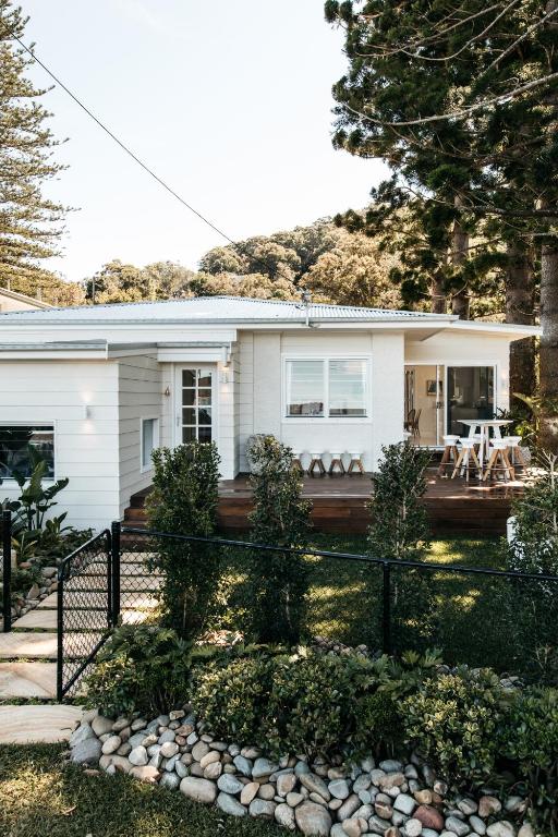 a white house with a fence in front of it at The Patonga Cottage in Patonga Beach