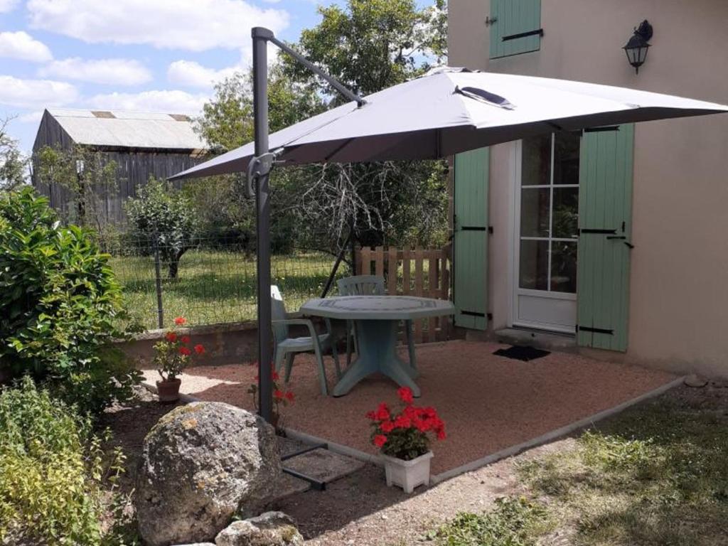 un patio con mesa y sombrilla en Gîte Neuvy, 2 pièces, 2 personnes - FR-1-489-10 en Neuvy