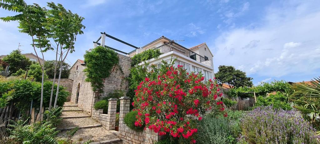 een huis met rode bloemen aan de zijkant bij Apartment Sea view in Vrboska