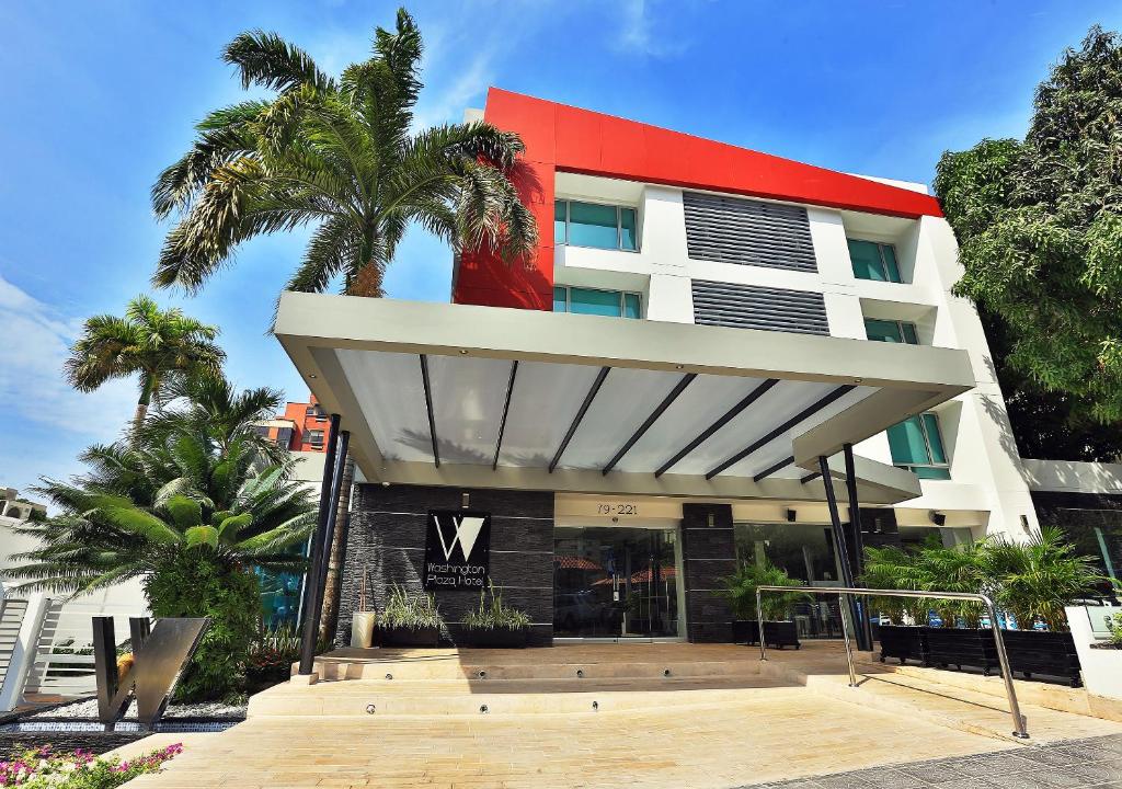 a hotel with a red and white building with a palm tree at Washington Plaza in Barranquilla