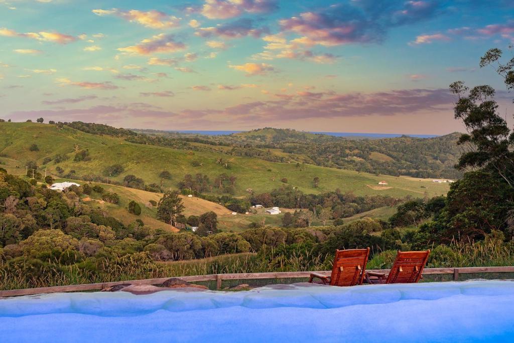 - deux chaises rouges installées à côté de la piscine dans l'établissement Rosecliffe Farm Cottages, à Pomona