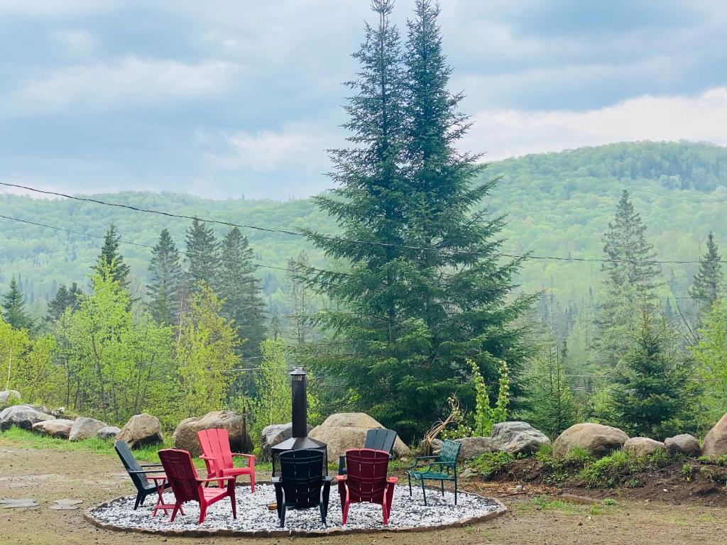 a group of chairs around a fire pit with a tree at Artemis Log Cabin with Spa & Mountain View in Sainte-Lucie-de-Doncaster
