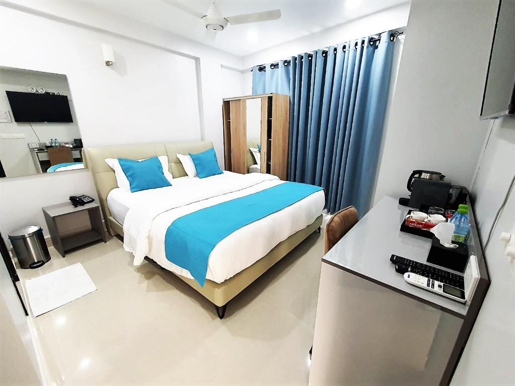 Schlafzimmer mit einem Bett mit blauen Kissen und einem Schreibtisch in der Unterkunft Tour Inn in Male City