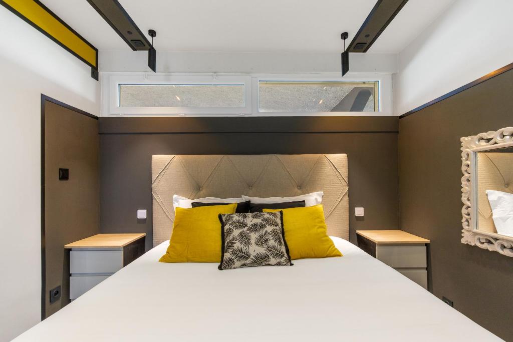 - une chambre avec un grand lit blanc et des oreillers jaunes dans l'établissement Honey trap Port Ambonne naturiste, au Cap d'Agde