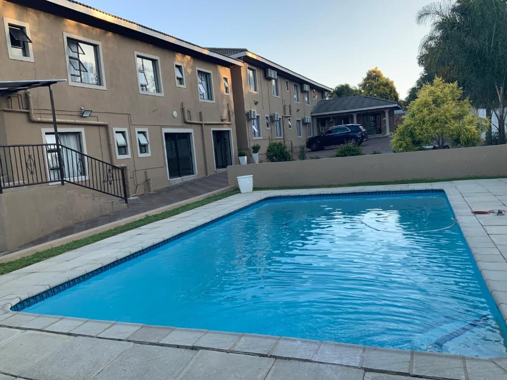 a large blue swimming pool in front of a building at La Bronze Guest Lodge in Newcastle