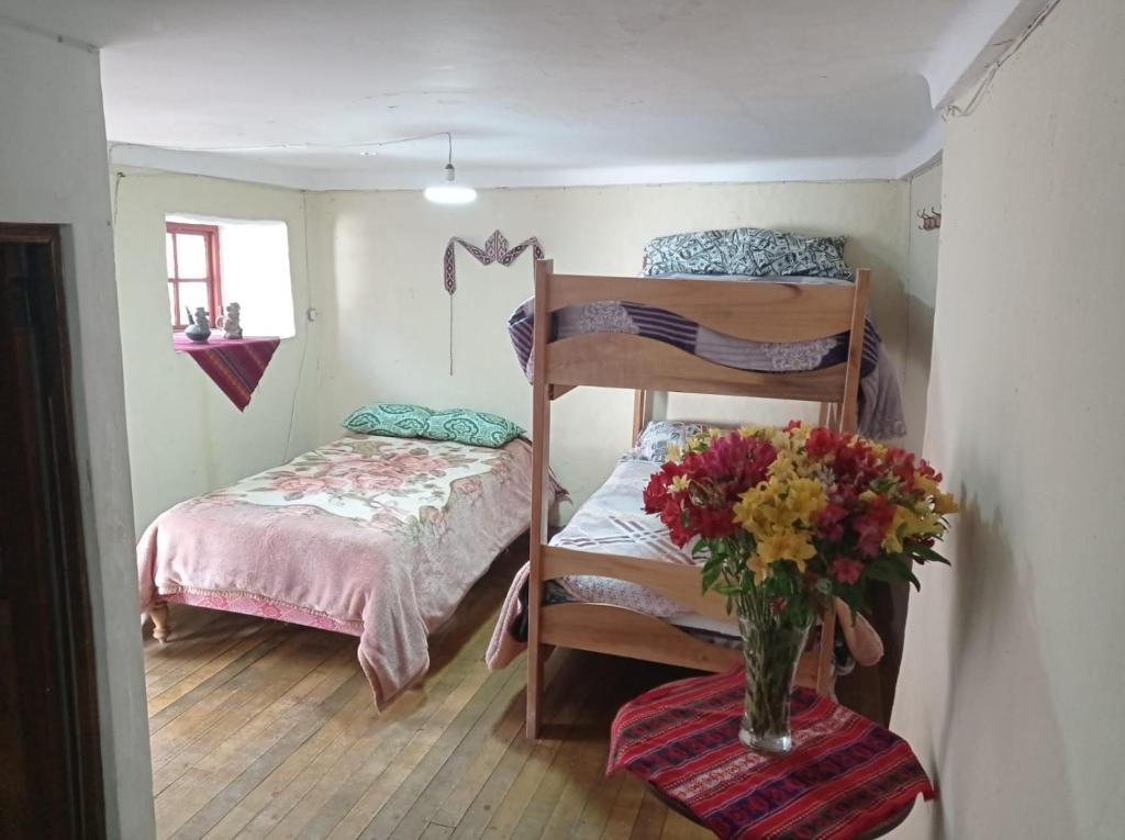a small bedroom with a bunk bed and a vase of flowers at CHINA SAQRA in Cusco