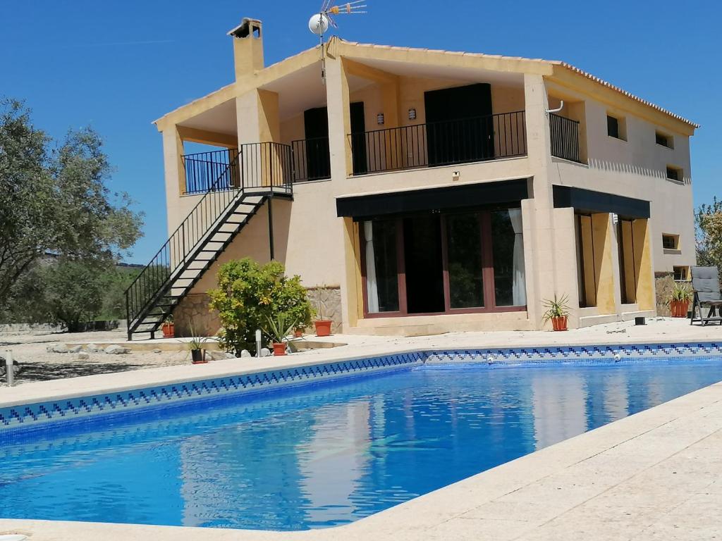 a villa with a swimming pool in front of a house at Habitaciones en Finca Olivo y Almendro in Ucenda