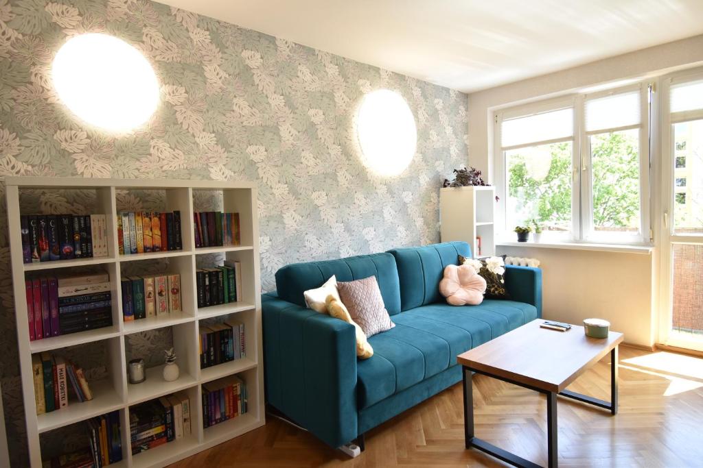 a living room with a blue couch and a book shelf at Lazurowe Przymorze in Gdańsk