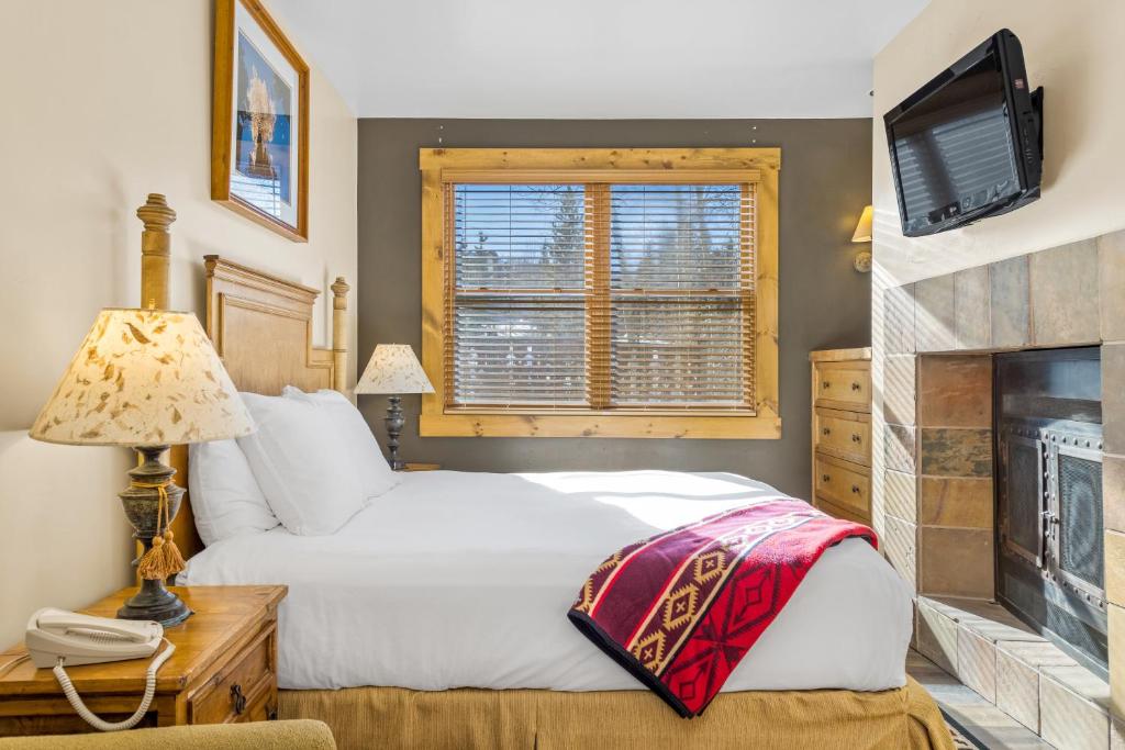 a bedroom with a white bed and a fireplace at Blue Collar Boutique: Affordable Adventure in Telluride
