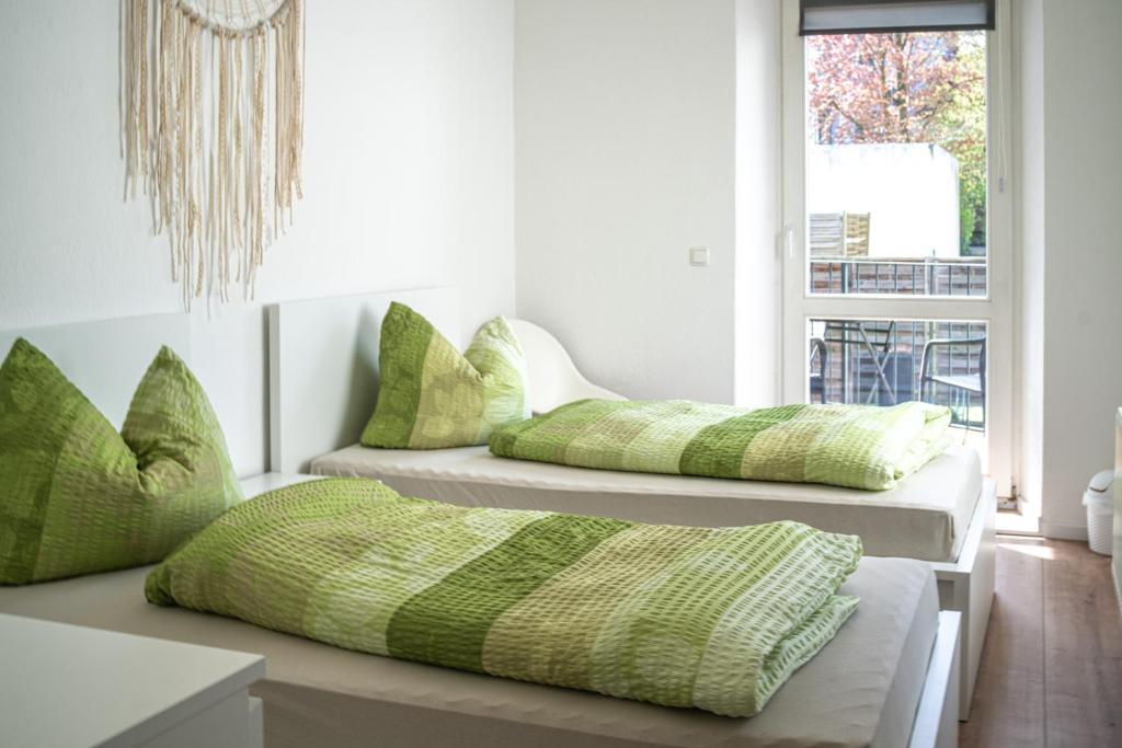 two beds in a room with green and white pillows at malerische Maisonettewohnung mit zwei Balkonen in Plauen