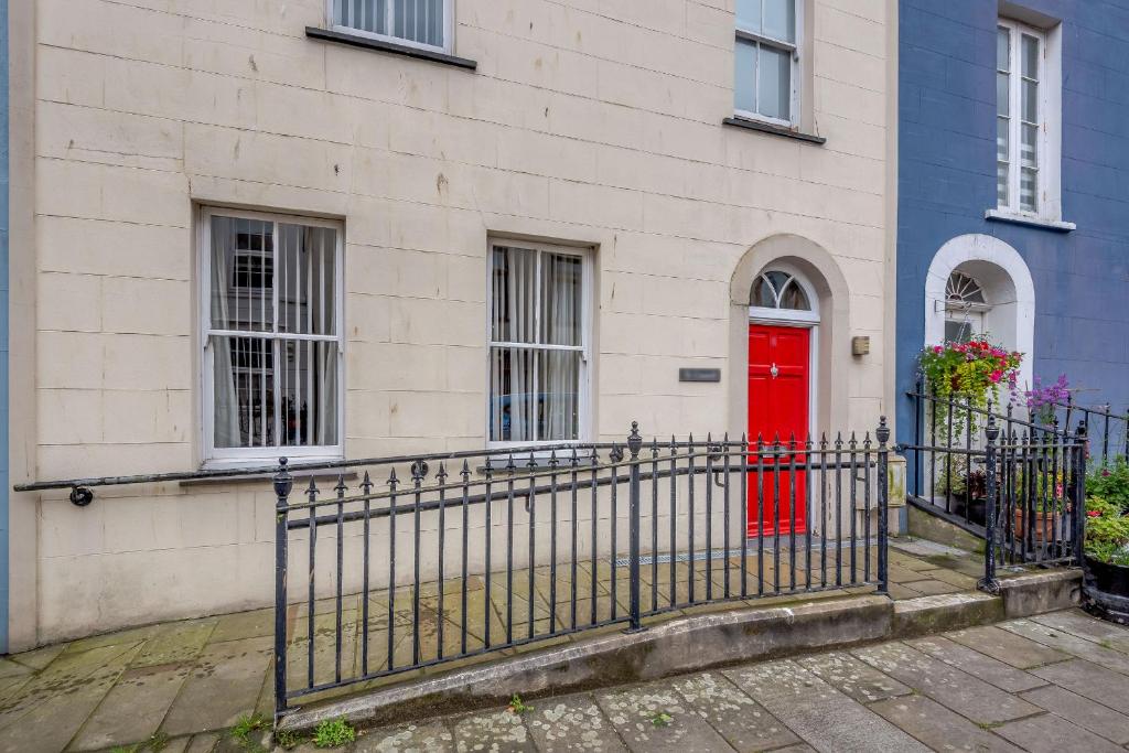 a red door on a house with a fence at Ty Castell in Caernarfon