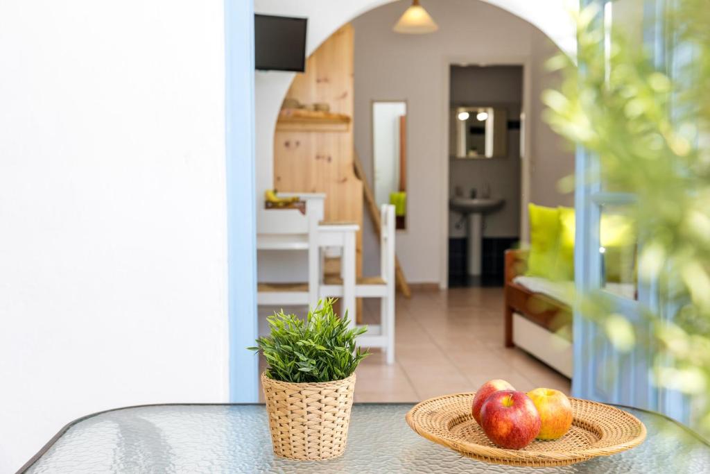 a table with a bowl of apples and a plant at Aqua Naxos Apartments & Suites in Naxos Chora