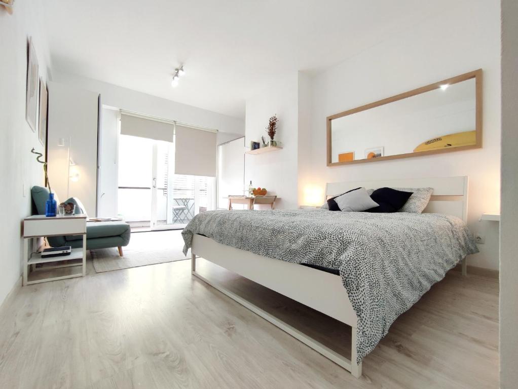 a white bedroom with a bed and a large mirror at Las Canteras Suite in Las Palmas de Gran Canaria