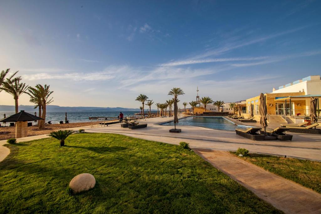 a resort with a pool and palm trees and the ocean at Luxotel Aqaba Beach Resort & Spa in Aqaba