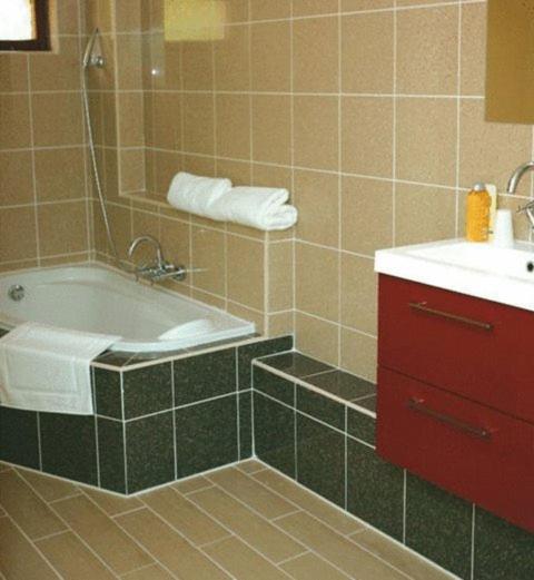 a bathroom with a tub and a sink and a red cabinet at La Tour Des Lys in Maubeuge
