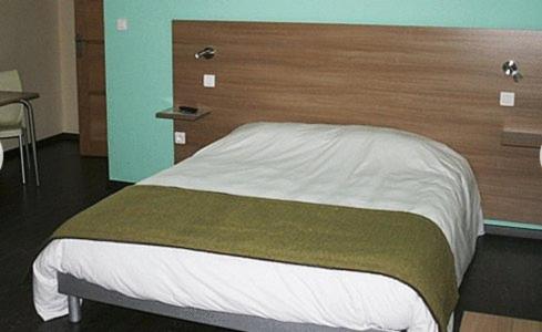 a bedroom with a bed with a wooden headboard at La Tour Des Lys in Maubeuge