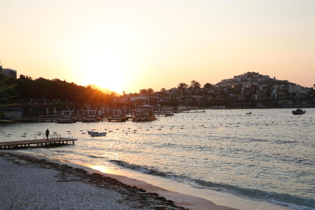 a beach with a pier and buildings and the sunset at Life Butiq Otel in Yalıkavak