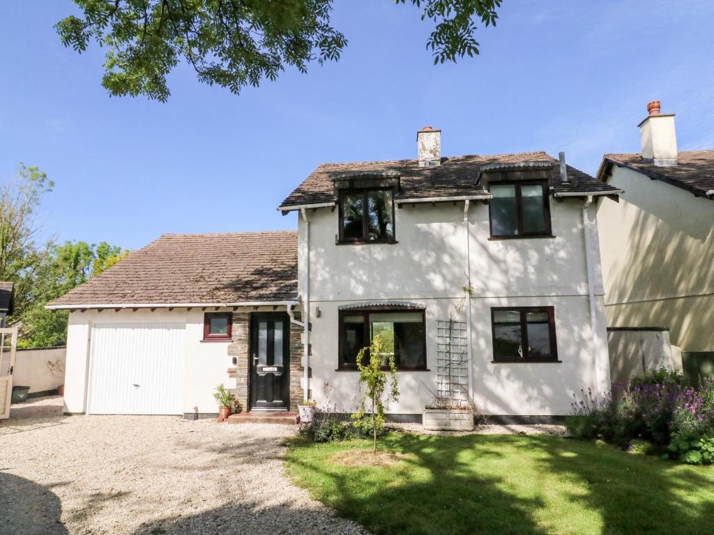 uma casa branca com uma garagem branca em Ash Tree Cottage em Holsworthy