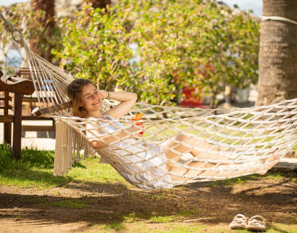 a woman laying in a hammock in a park at CHARM BEACH HOTEL in Akyarlar