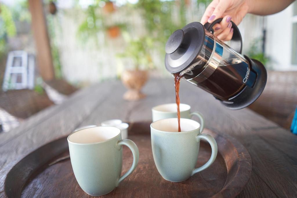 a person pouring coffee into two cups on a table at Serenity Luxurious Beachfront Villa & Spa with private Infinity Pool, 8 Guests in Gili Air