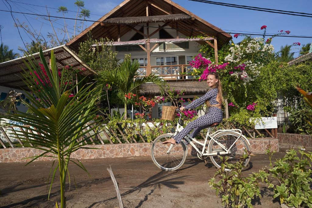 a woman riding a white bike in front of a house at Serenity Luxurious Beachfront Villa & Spa with private Infinity Pool, 8 Guests in Gili Air