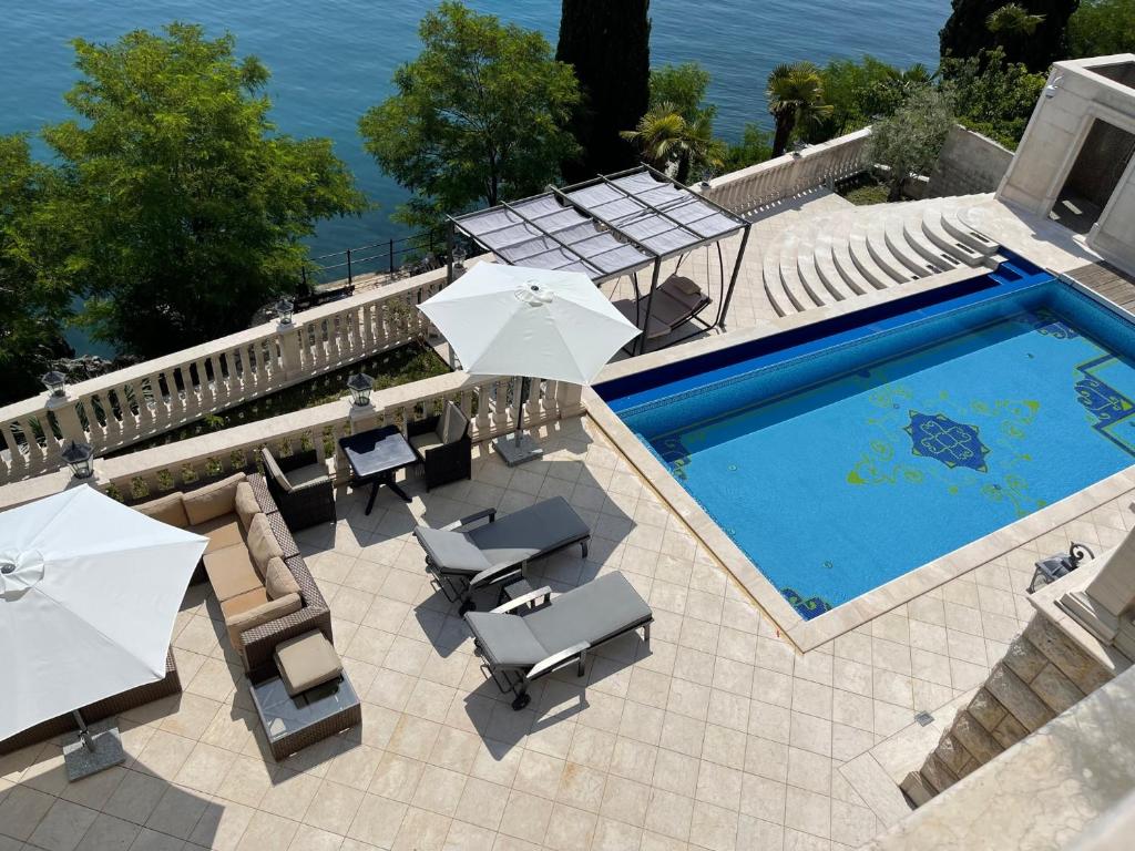 a swimming pool with umbrellas and chairs and a swimming pool at Apartments Villa Isabella in Opatija
