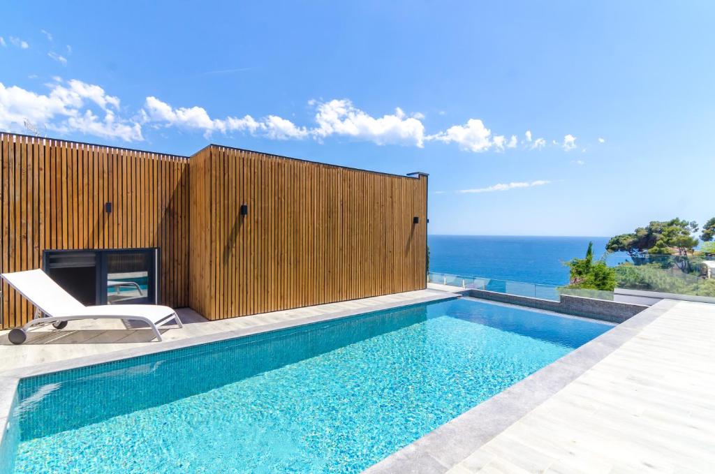 een zwembad met een stoel naast een houten hek bij 4 bedrooms villa at Lloret de Mar 100 m away from the beach with sea view private pool and enclosed garden in Lloret de Mar