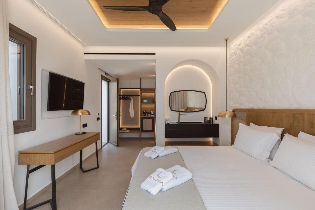 um quarto com uma cama, uma secretária e uma televisão em Calma Suites Mykonos em Psarou