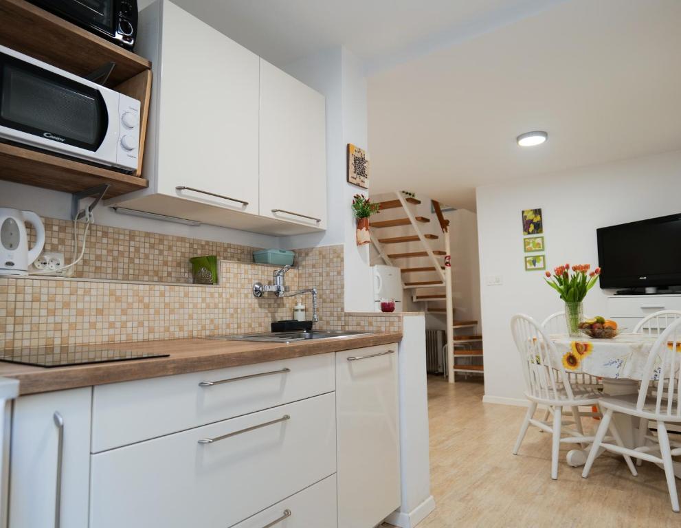 een keuken met witte kasten en een tafel met stoelen bij Apartment or room at Irena's in Piran